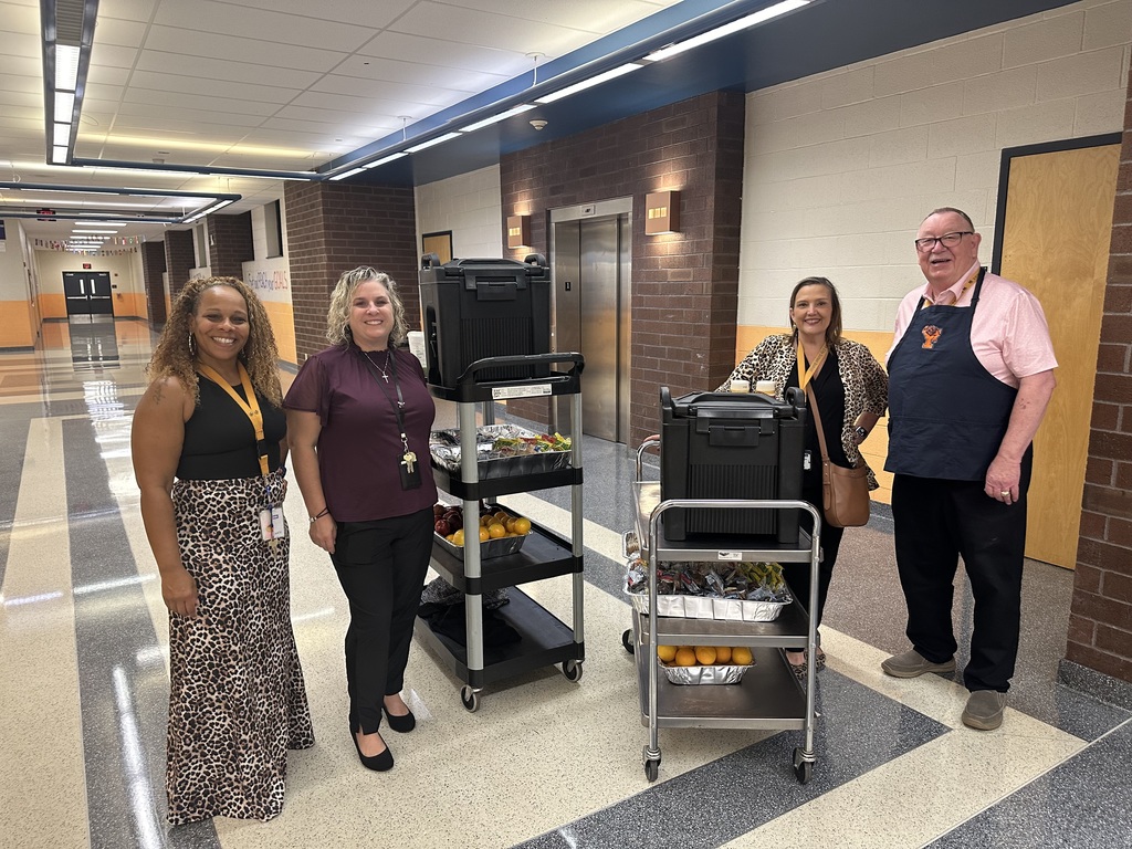 Four district staff members pushing carts with fruit, coffee, and other snacks.