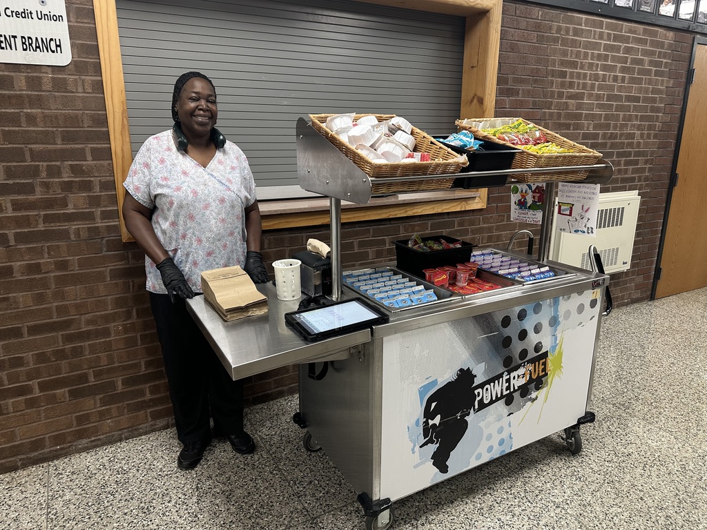 A district staff member posing in front of a Power Fuel snack cart.