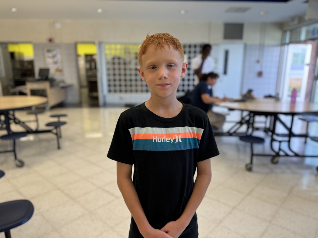 A Hannah Penn student posing for a photo at Hannah Penn's recent Back to School Night. Two people can be seen in the background.
