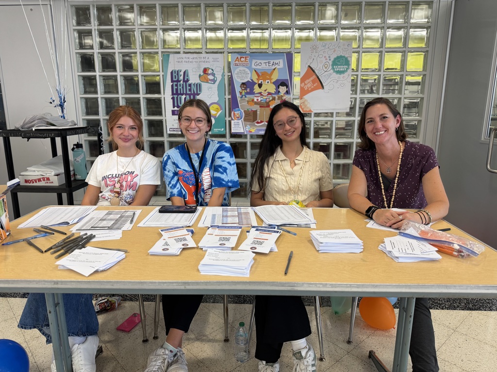 Four district staff members sitting behind a table with multiple papers, brochures and pens at Hannah Penn's recent Back to School Night.