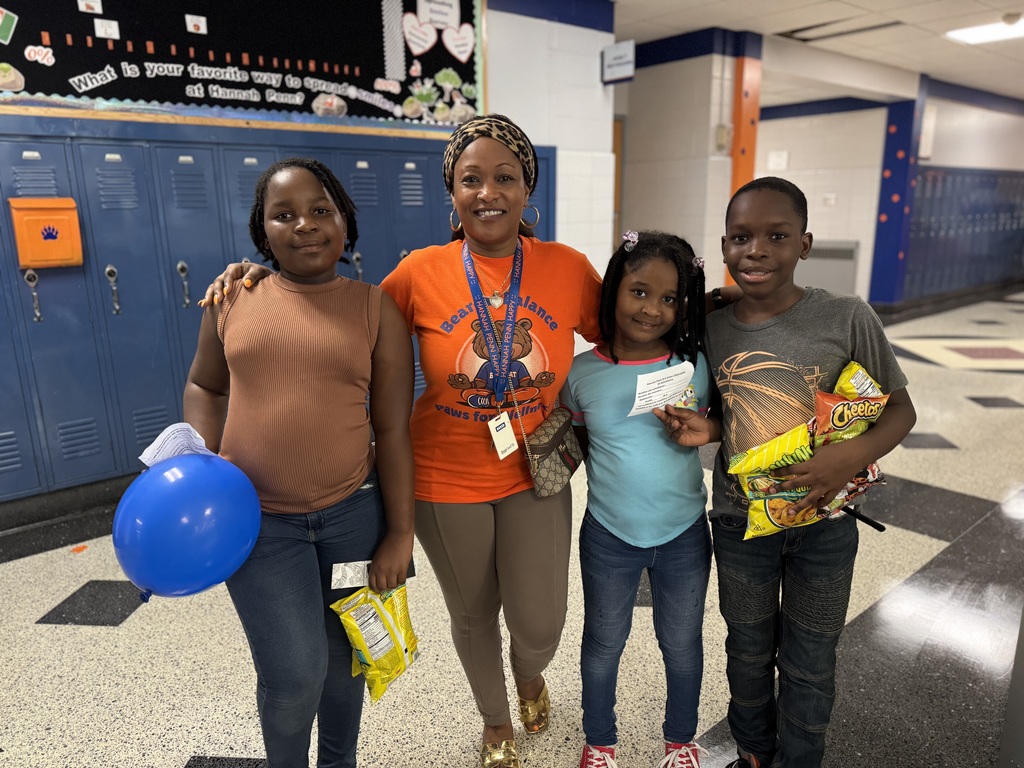 Hannah Penn PreK-8's Assistant Principal Merisca with three Hannah Penn students at their recent Back to School Night. One of the students is holding a balloon and two bags of chips in her hand and another student is holding a piece of paper in his hand and three bags of chips.