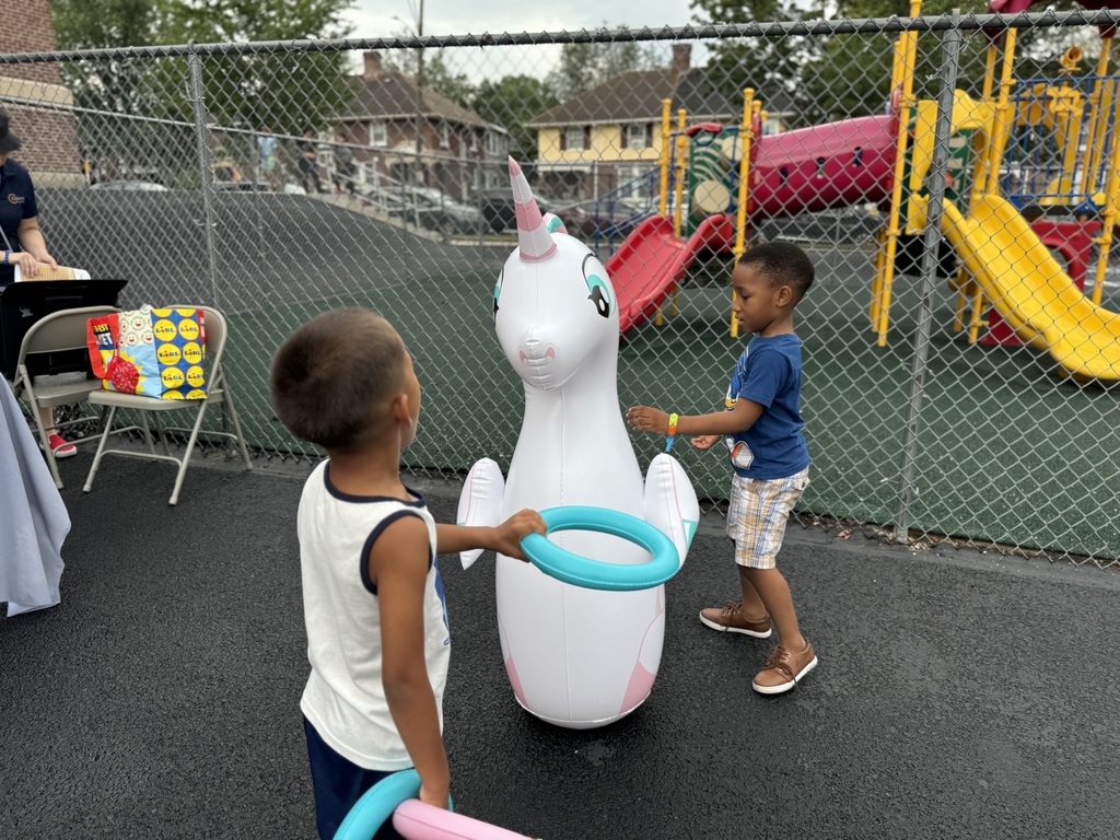 Two students playing with a unicorn. One student is getting ready to throw a ring on the unicorn.