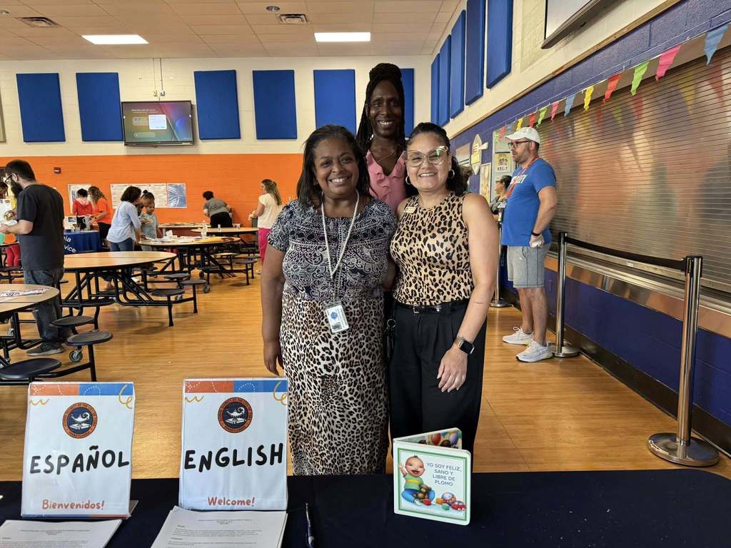 Superintendent of Schools, Dr. Andrea Berry-Brown and district parent liaisons, Ms. Walker and Ms. Torres Ocasio standing behind a table with two papers labeled English and Espanol.
