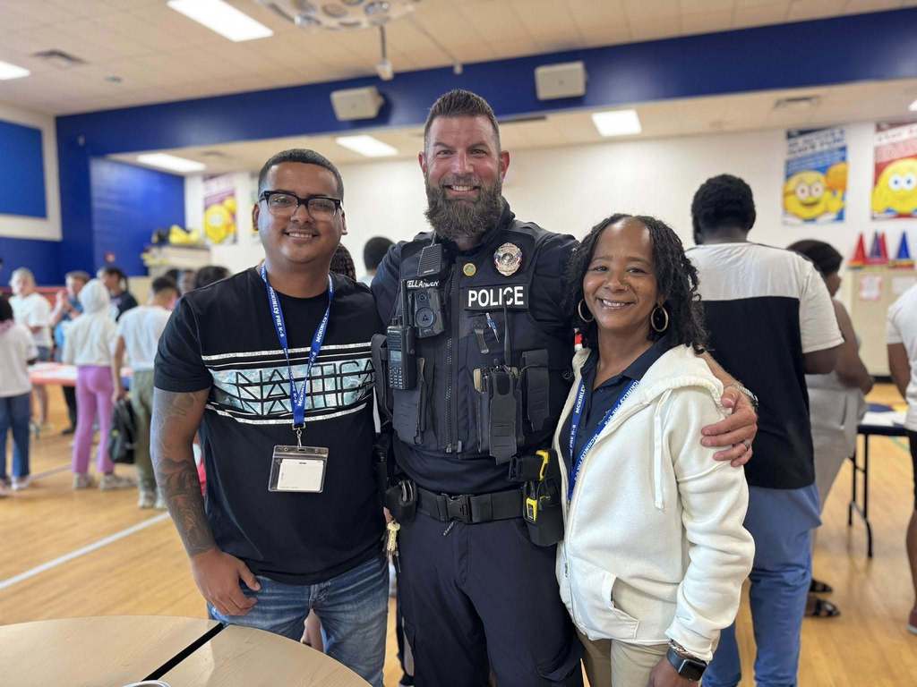 District staff posing together for a photo. People can be seen in the background.