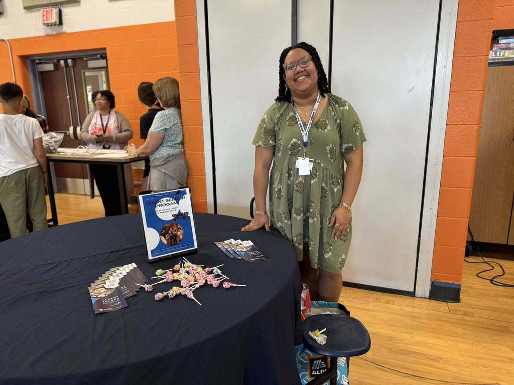 A district staff member standing next to a table with candy and brochures on it. 