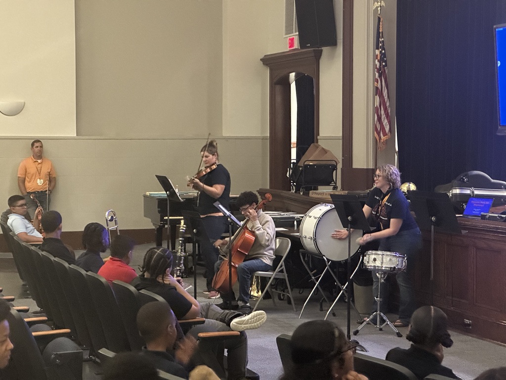 District staff members and a student playing instruments during the district's annual K-8 Music Recruitment Assembly.