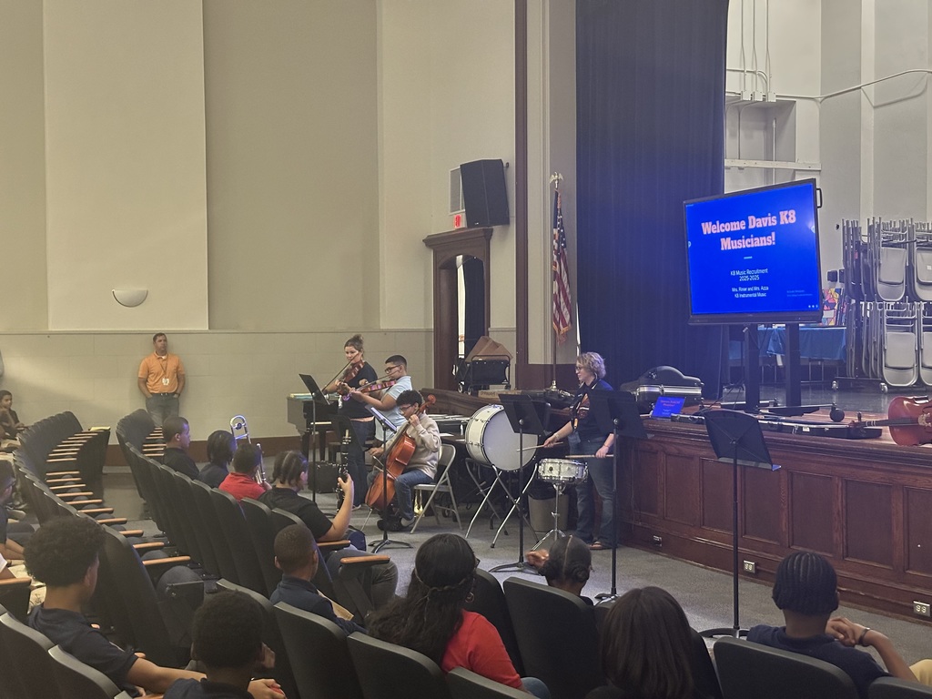 District staff members and two students playing instruments during the district's annual K-8 Music Recruitment Assembly.