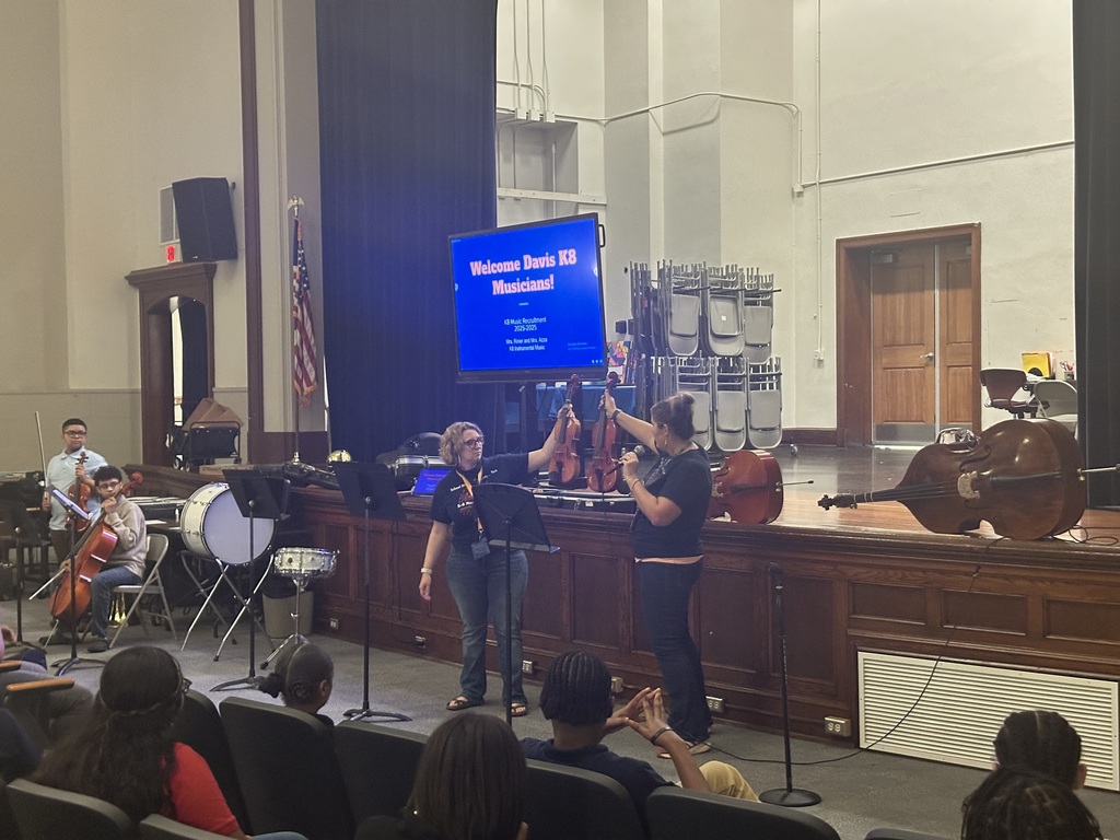 District staff members holding up instruments during the district's annual K-8 Music Recruitment Assembly.
