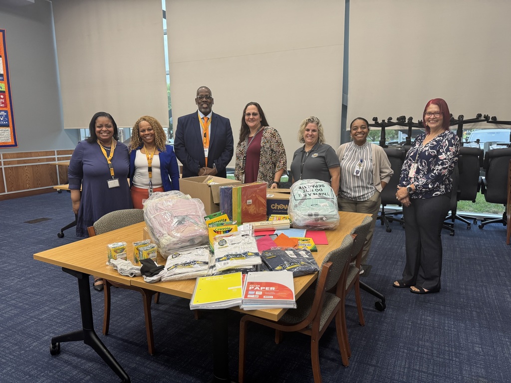 District leadership and employees from York County Children, Youth and Families posing in front a table filled with school supplies, including backpacks, notebooks, and Crayola packs.