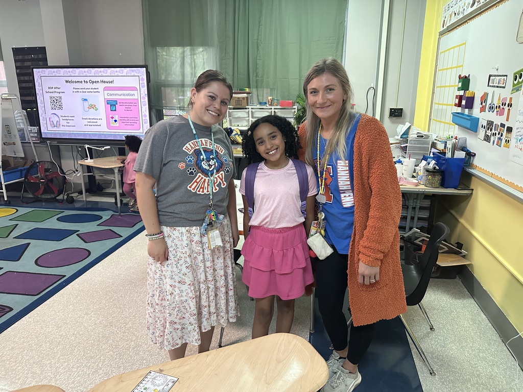 Two district staff members and a student posing for a photo in a classroom.