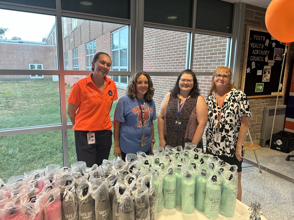 District staff members posing for a group photo in front of a table that has water bottles on it. 
