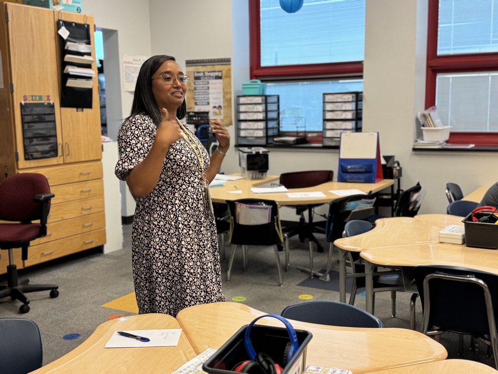 A district staff member standing with her hands up in a classroom.