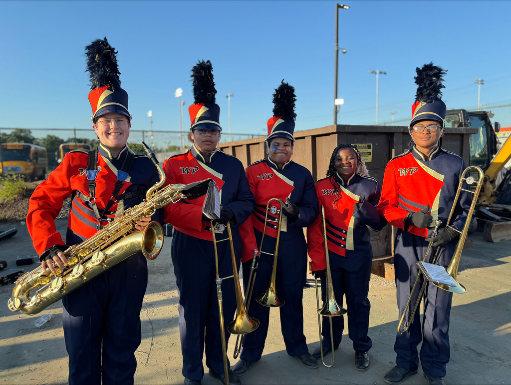 A group of five York High band members dressed in red and blue uniforms, holding brass instruments, with a clear blue sky in the background.