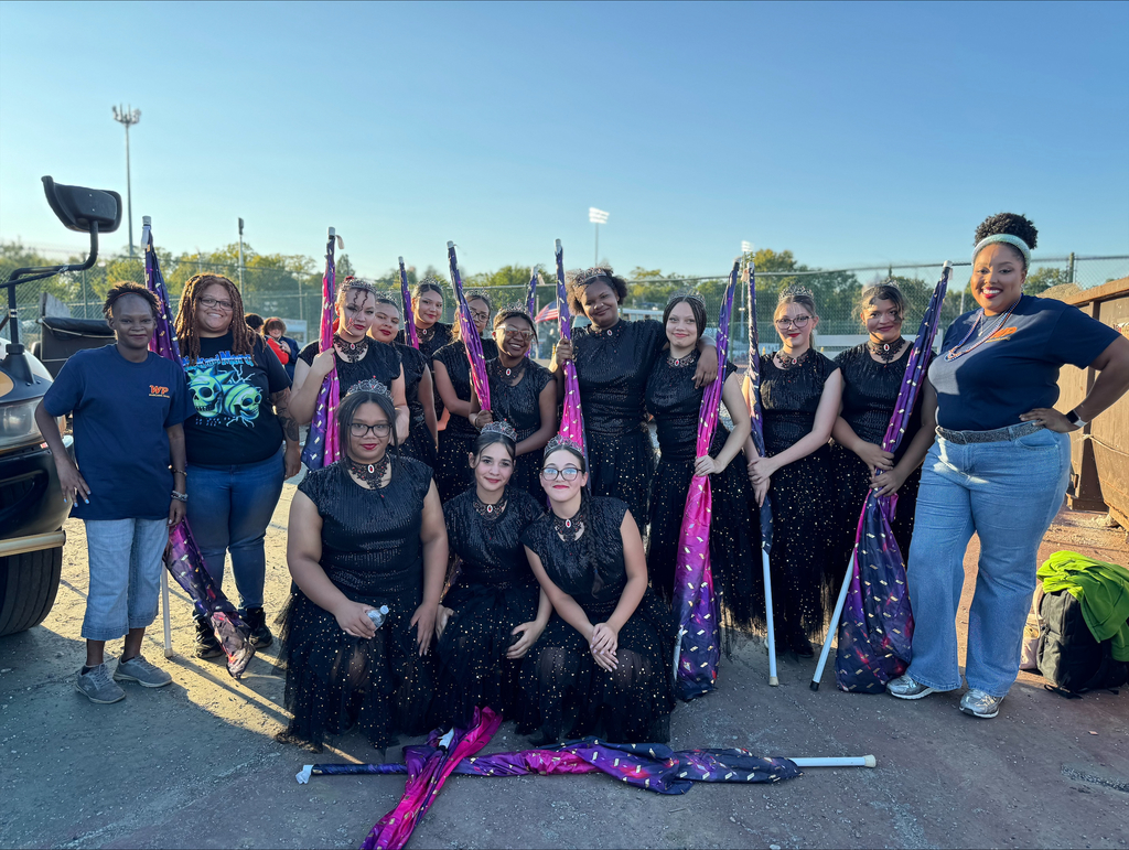 York High Color Guard posing with their flags in an outdoor setting. People can be seen in the background.