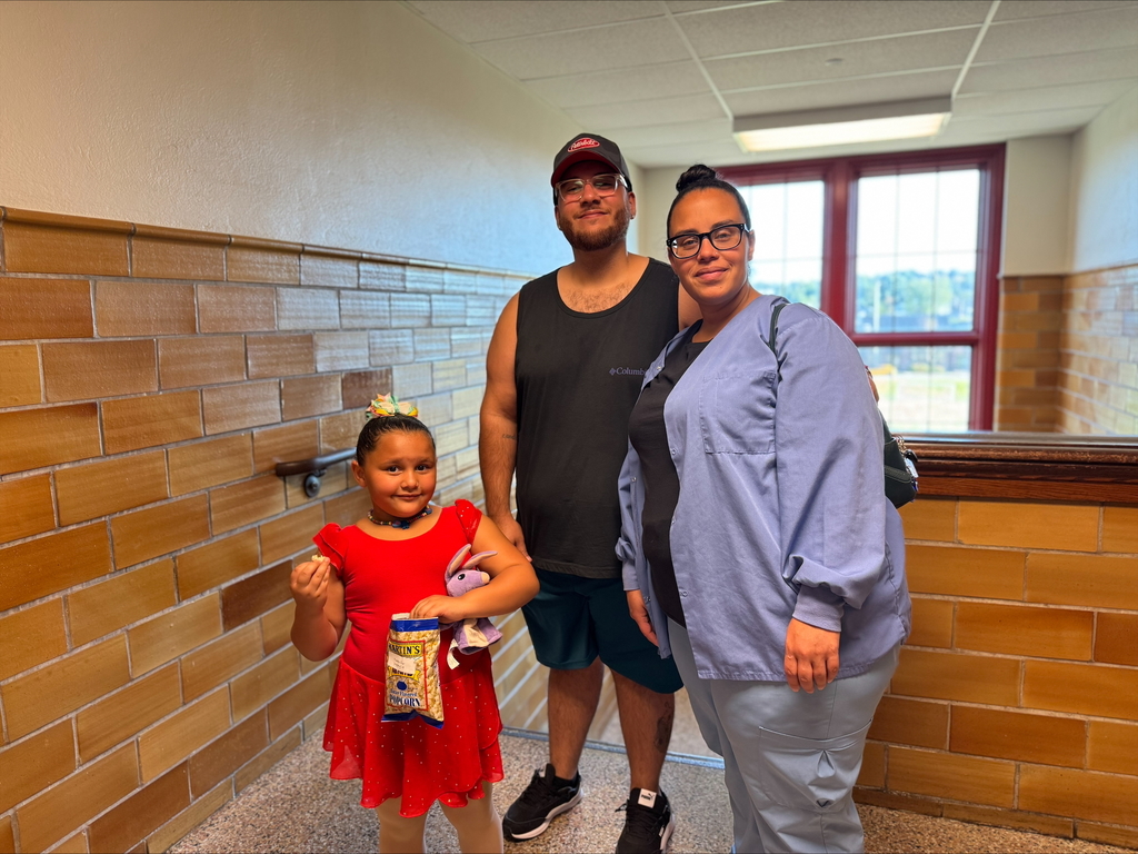 A family of three, two adults and one child are posing together near a staircase and a large window.