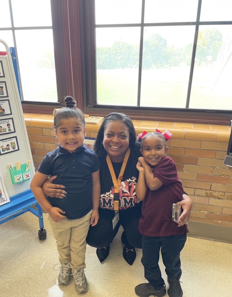 Dr. Andrea Berry-Brown, Superintendent of Schools, crouching in between two young students in a classroom.
