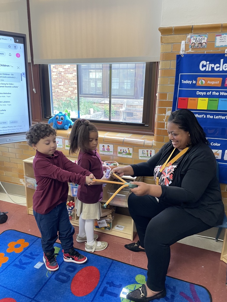 Dr. Andrea Berry-Brown, Superintendent of Schools and two young students are playing with a toy together in a classroom.