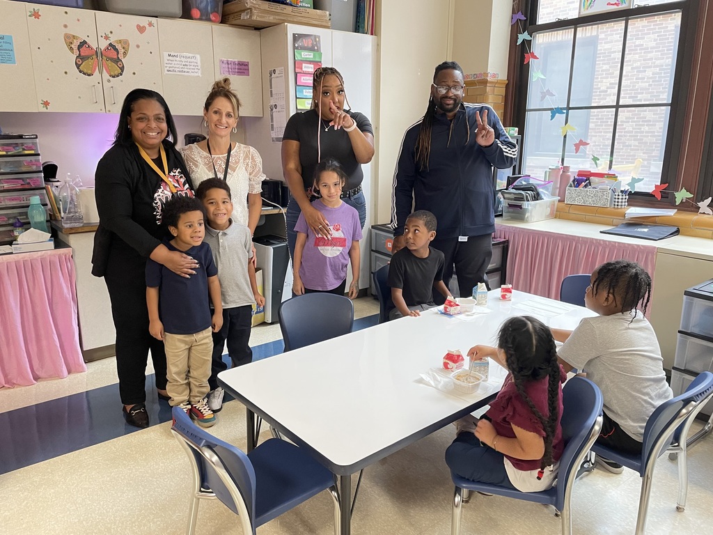Dr. Andrea Berry-Brown, Superintendent of Schools and three district staff members are standing in a classroom with a group of six students. Three of the students are sitting down at a table with chairs.