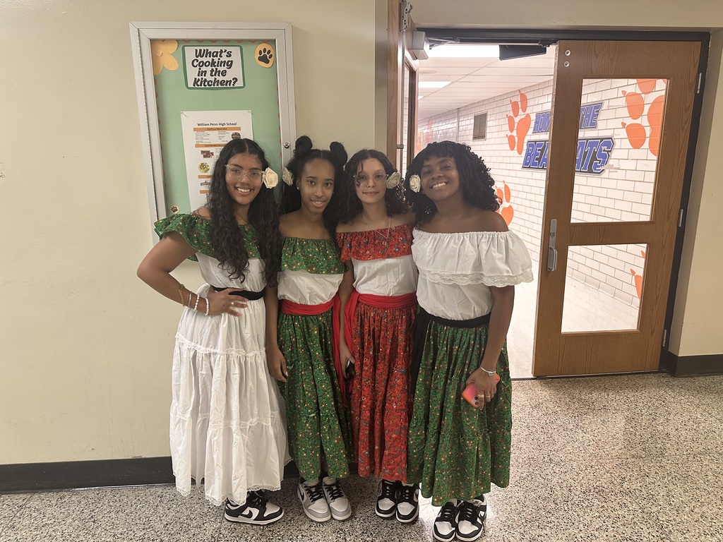 Four students standing in a hallway dressed in cultural clothing for Hispanic Heritage Month.
