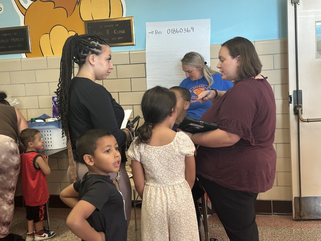 Devers PreK-8's Assistant Principal, Ms. Keesey is assisting an adult in a lobby area while other kids are standing nearby. Other people can be seen in the background.