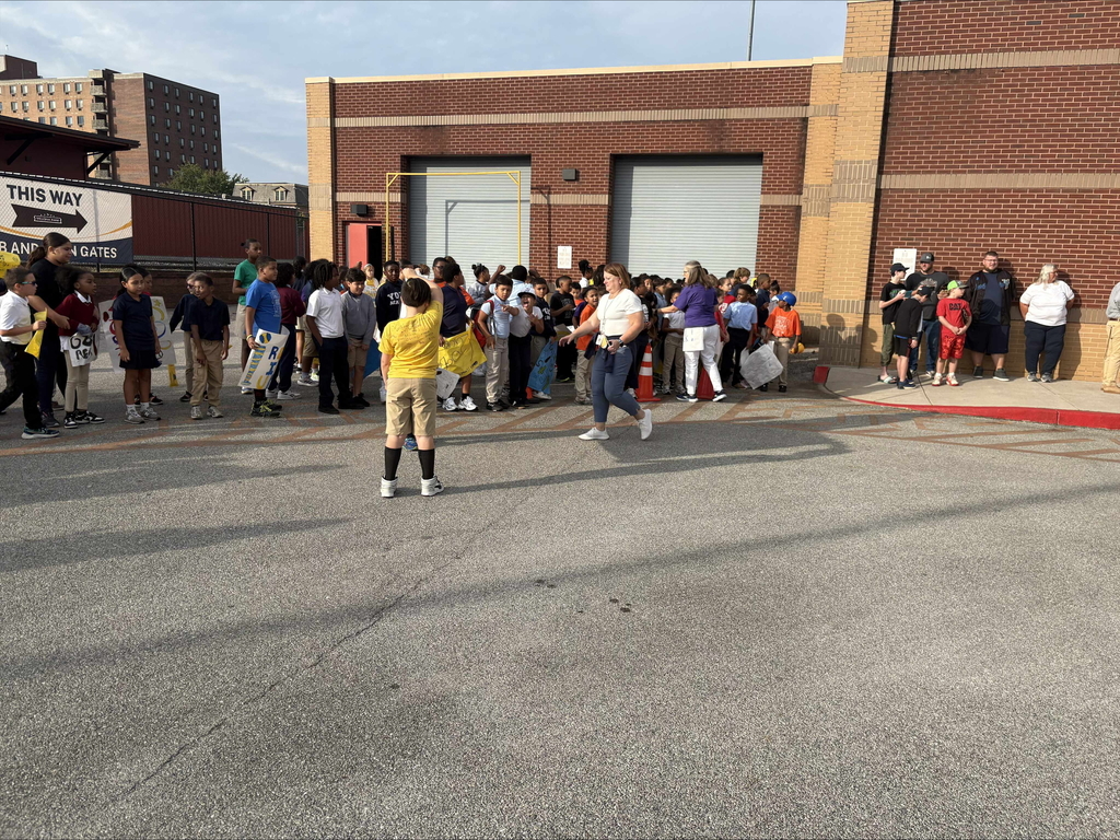 A group of people standing outside in a parking lot area cheering with signs and posters.