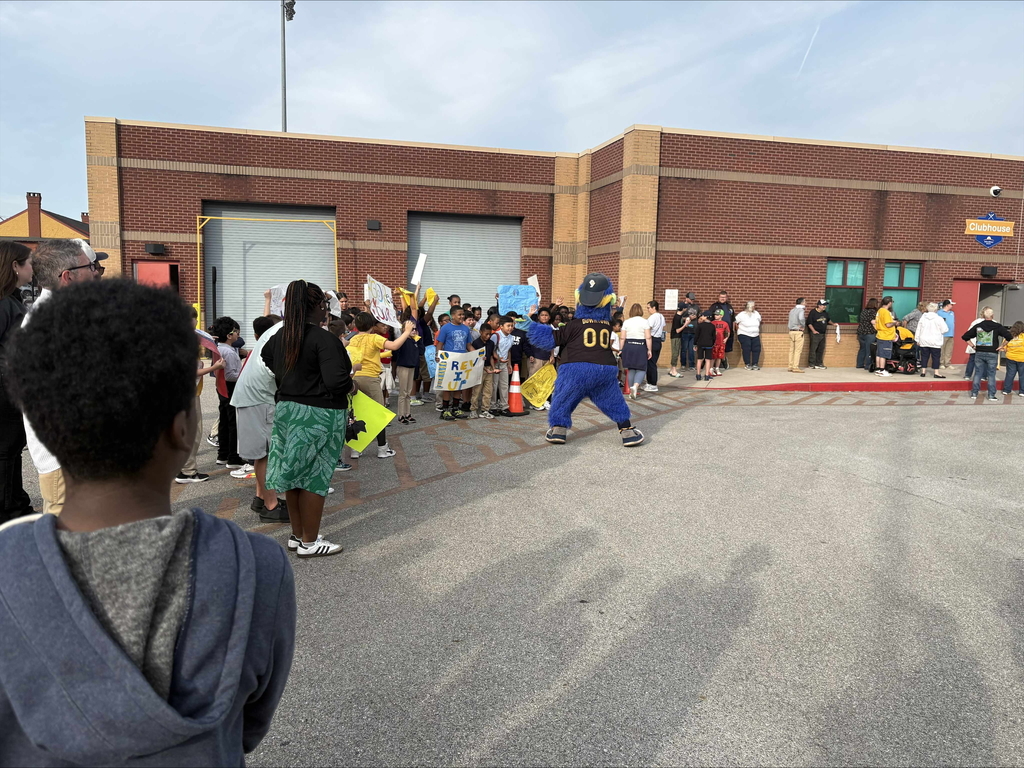 A group of people standing outside in a parking lot area cheering with signs and posters.