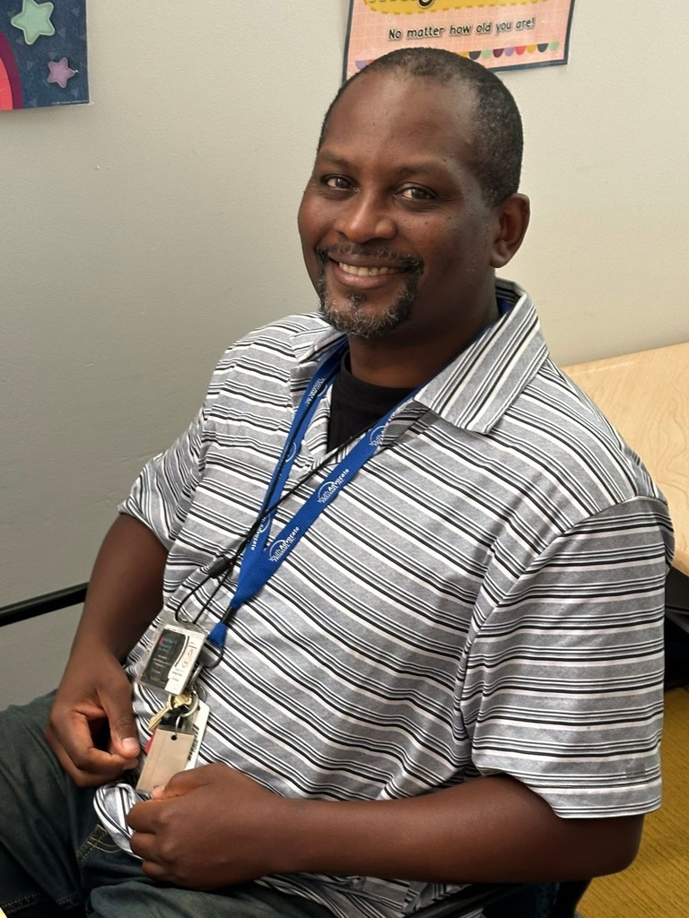 A district staff member smiling and sitting down in a chair.