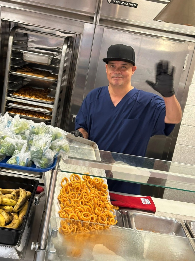 A district staff member waving his hand. Food can be seen nearby.