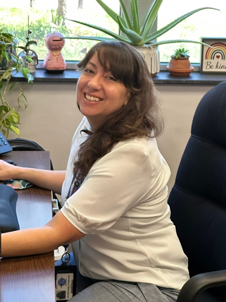 A district staff member smiling and sitting down in a chair.