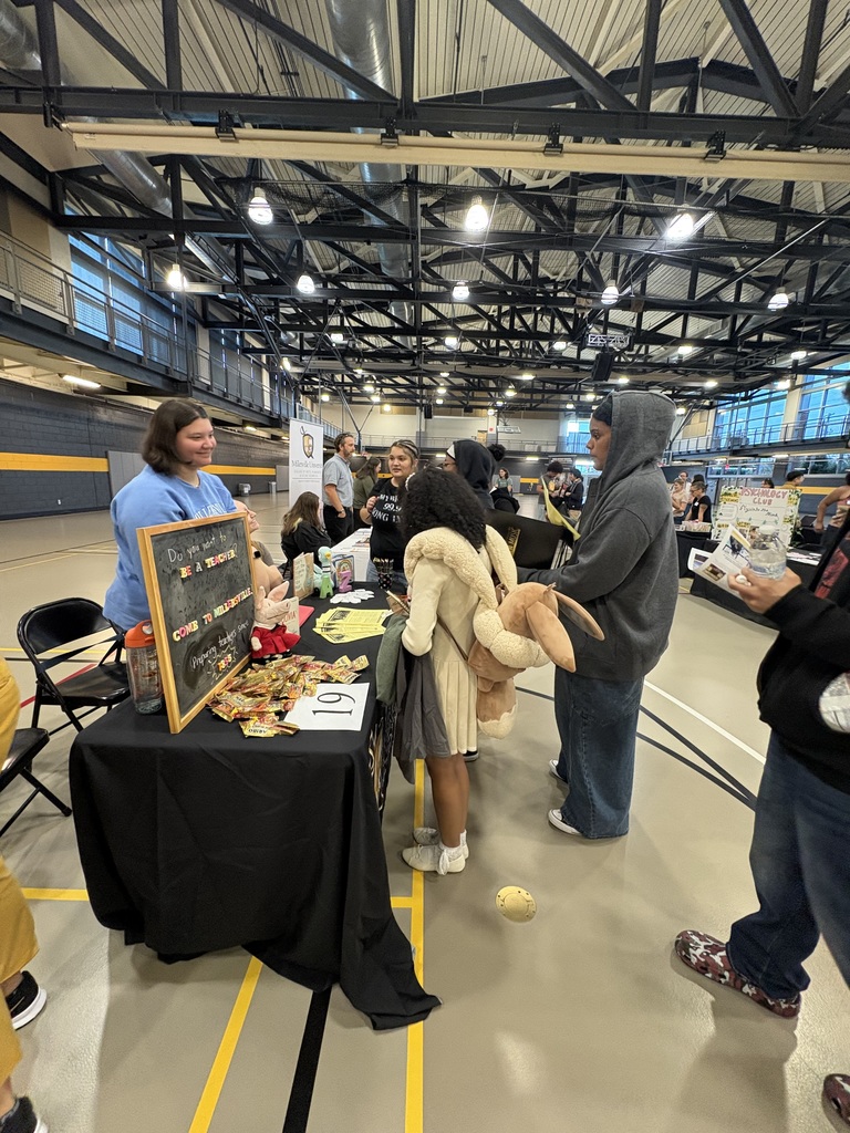 A group of William Penn Senior High School students standing near a table that has candy and brochures on it.
