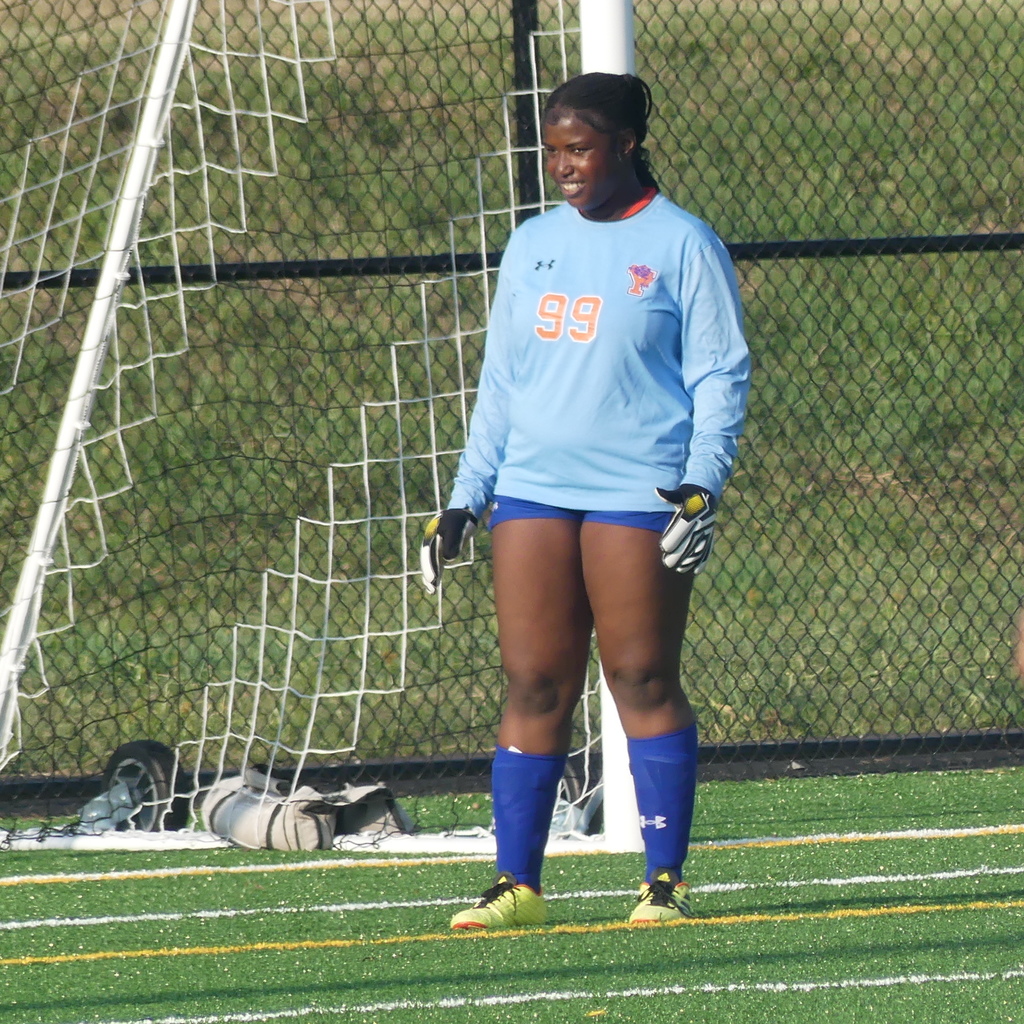 York High Girls Soccer player standing outside on the field near a white net.