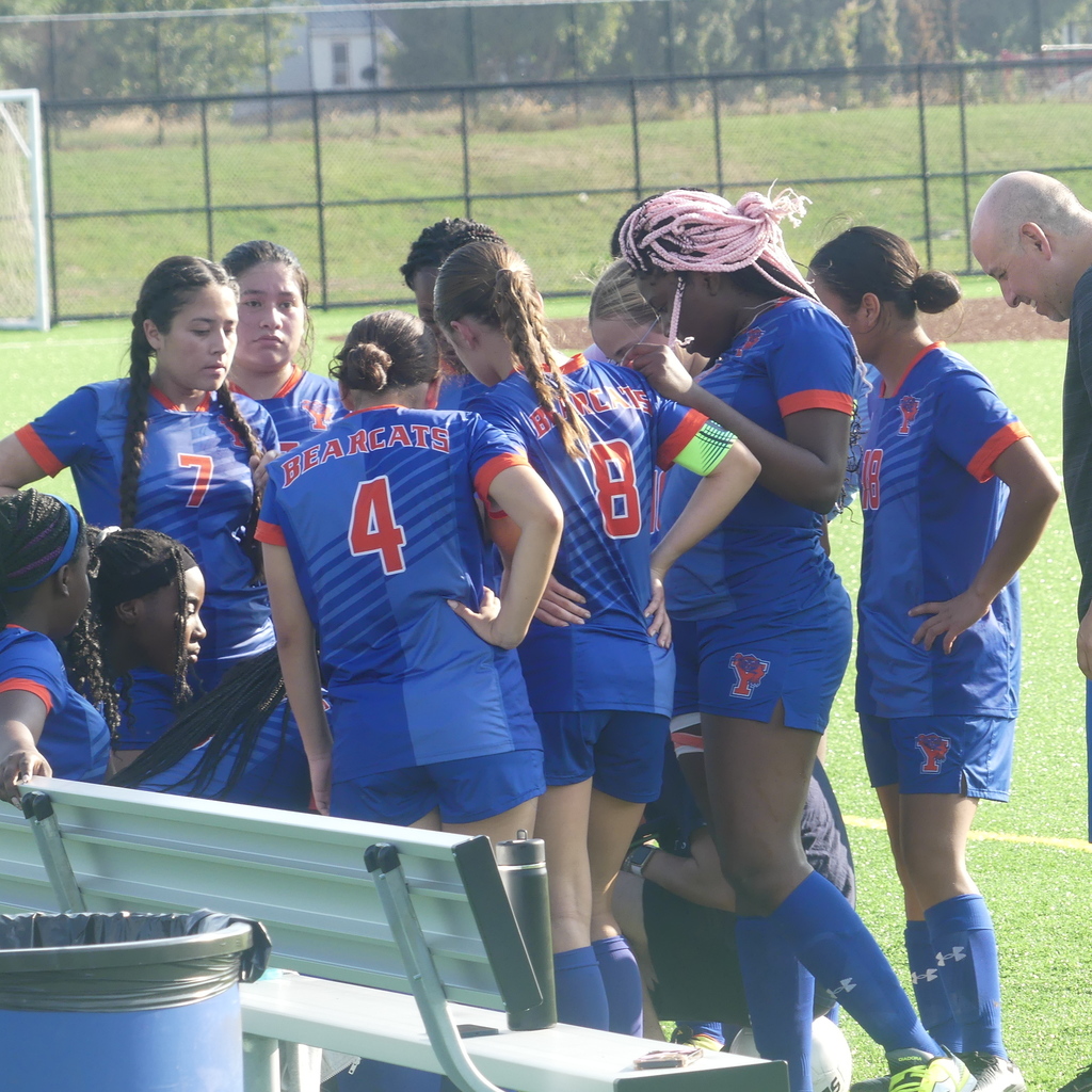York High Girls Soccer Team crowding together outside on the field.