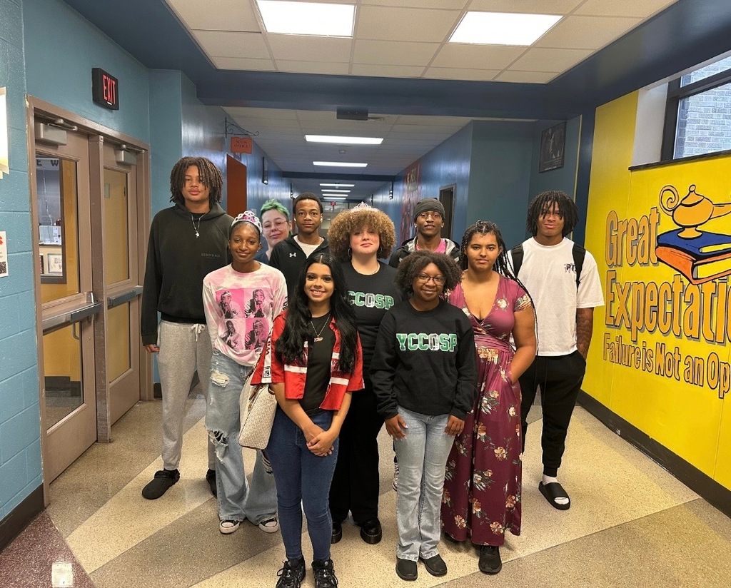Ten William Penn Senior High School students standing in a school hallway next to a mural on a wall that reads "Great Expectations." 