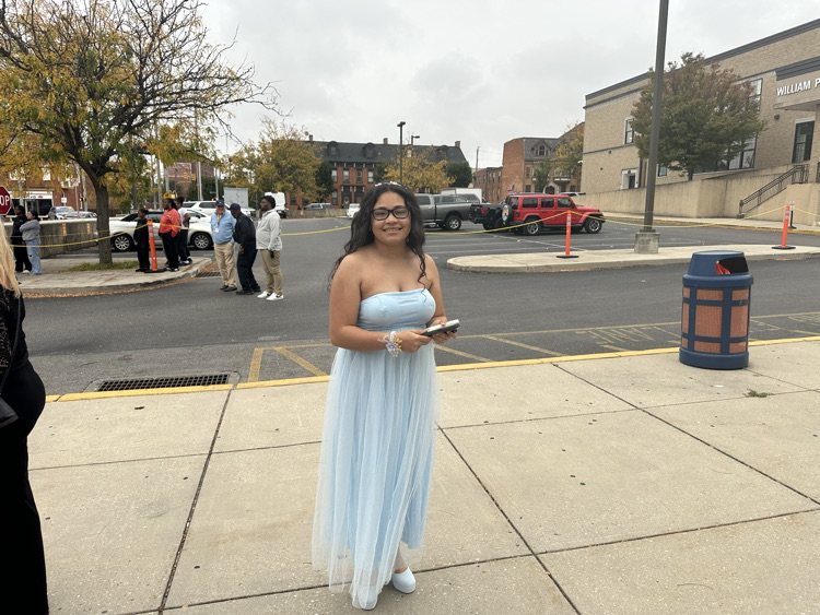A student is posing outside at William Penn Senior High School’s 2025 Homecoming. Cars and other people can be seen in the background.