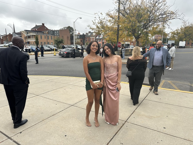 Two students are posing together outside at William Penn Senior High School’s 2025 Homecoming. Cars and other people can be seen in the background.