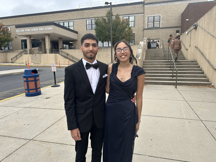 Two students are posing together outside at William Penn Senior High School’s 2025 Homecoming. Other people can be seen in the background.