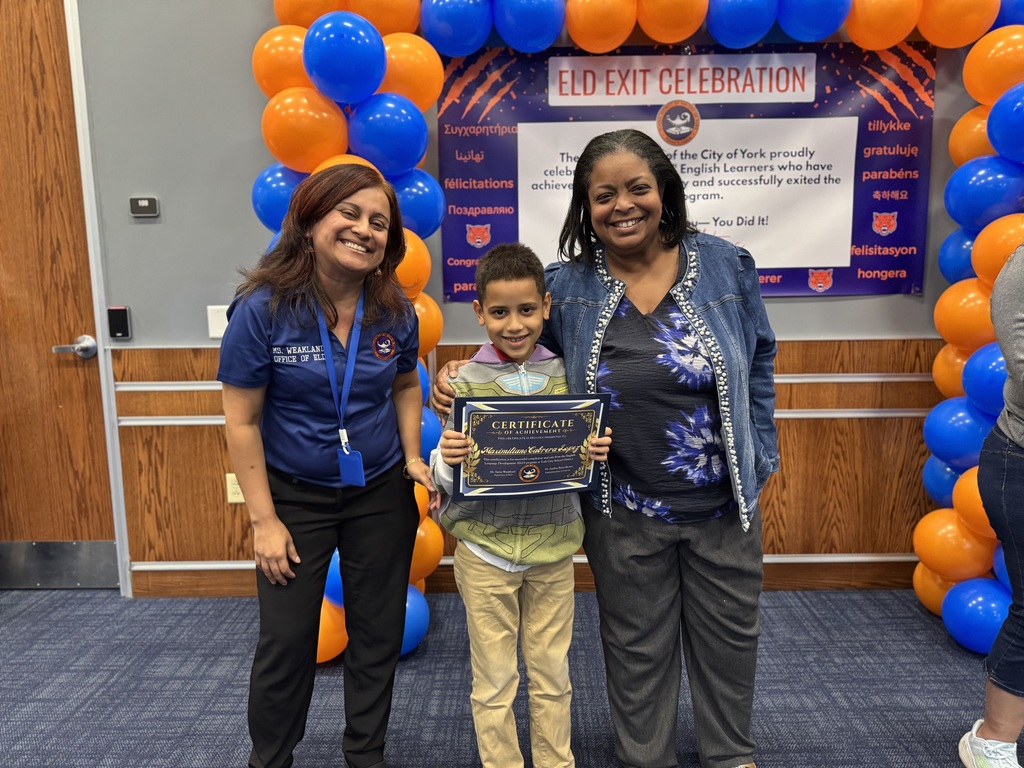 Superintendent of Schools, Dr. Andrea Berry-Brown and the district's Supervisor of ELD, Ms. Weakland posing with a student who is holding a certificate while standing in front of a banner with orange and blue balloons. The top of the banner says "ELD EXIT CELEBRATION".