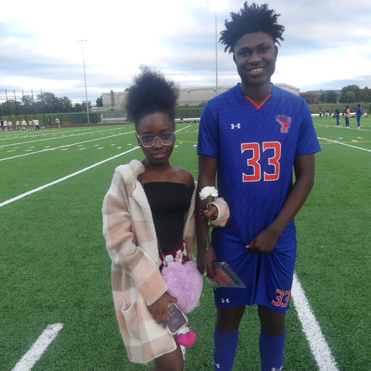 A York High Boys Soccer team player and a girl standing outside on a field.