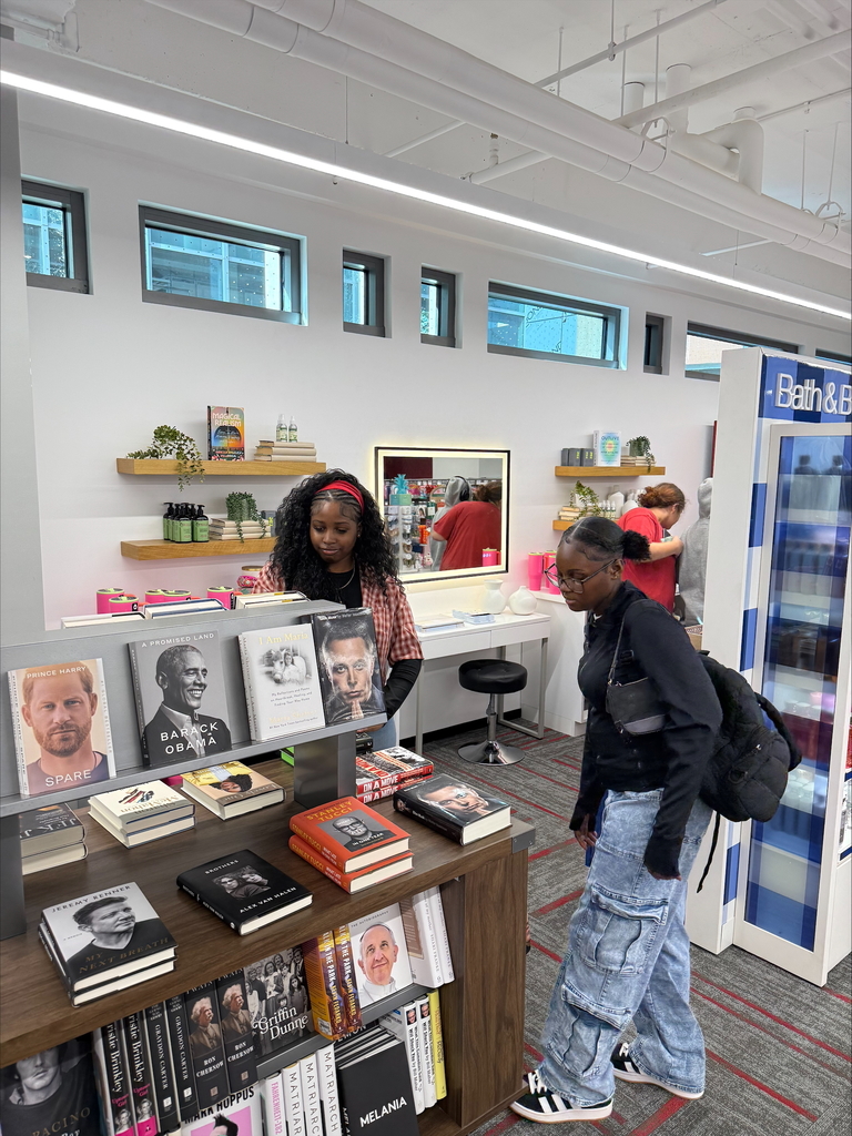 Two young women are browsing a bookstore with biographies on display.