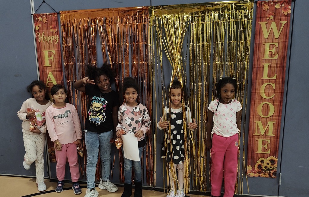 A group of six students are posing in front of a festive gold and orange tinsel backdrop that says "Happy Fall Y'all" and "Welcome" on the sides. 