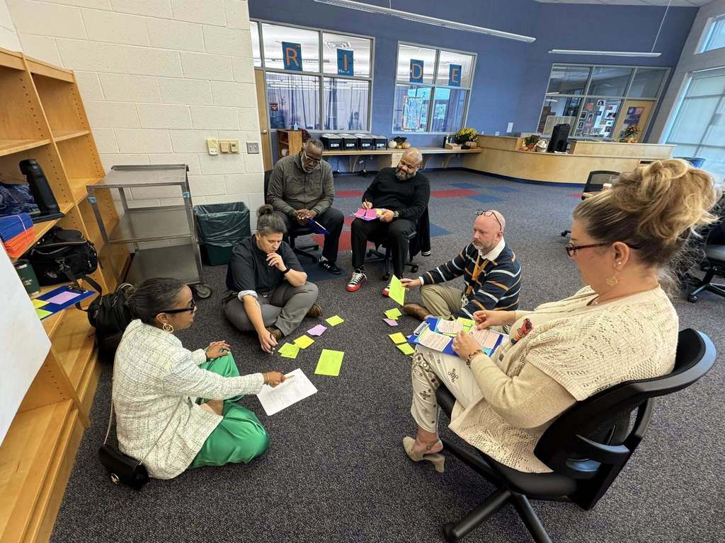 A group of district staff members are having a discussion in a large area.