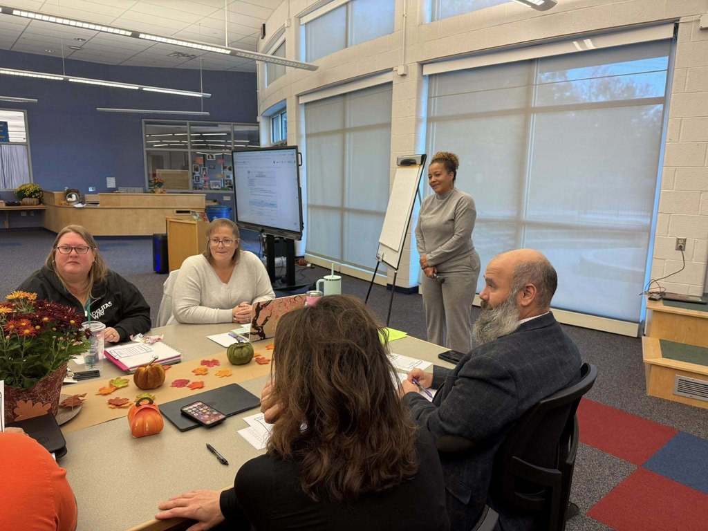 A group of district staff members are having a discussion in a conference room.