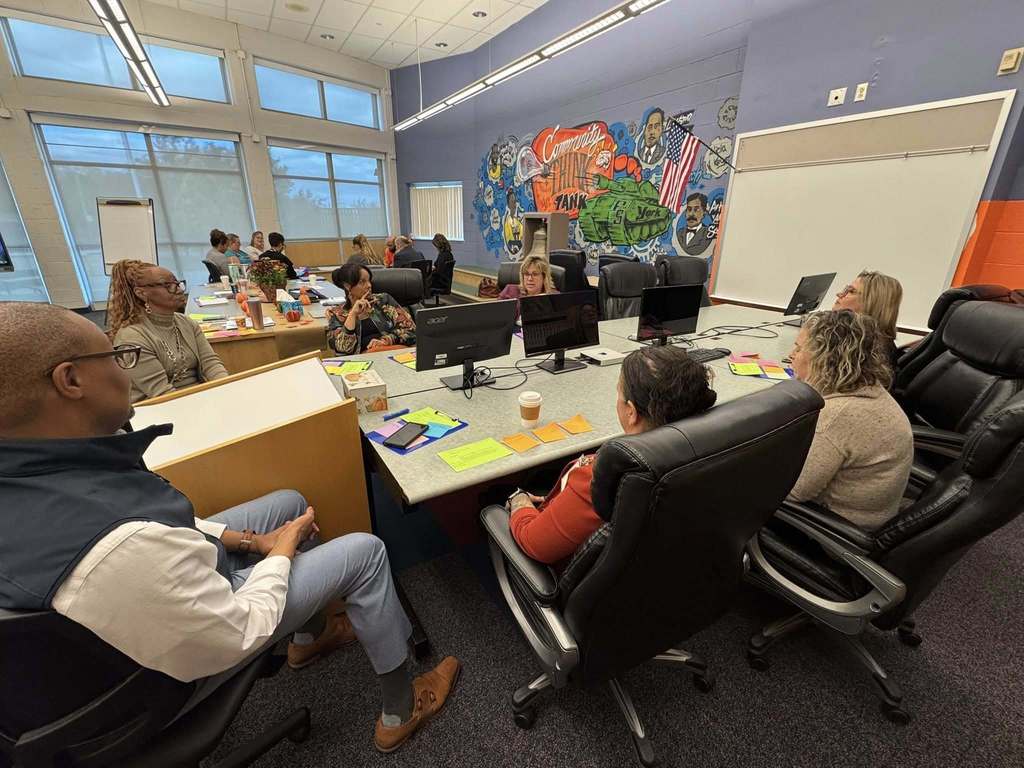 A group of district staff members are having a discussion in a conference room.
