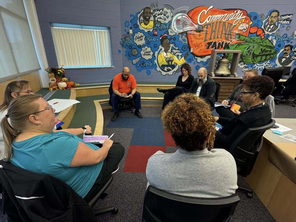A group of district staff members are having a discussion in a conference room.