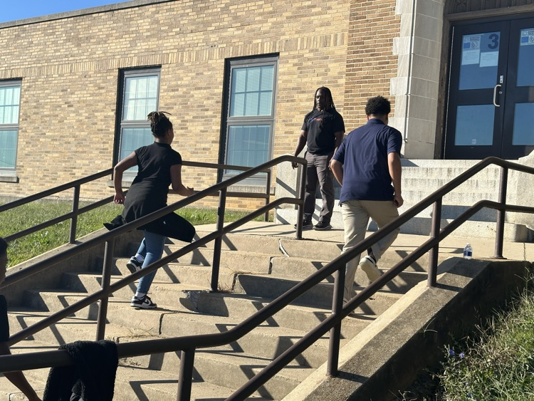 A group of students running up a flight of stairs outside while