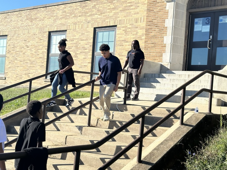 A group of students running down a flight of stairs outside while