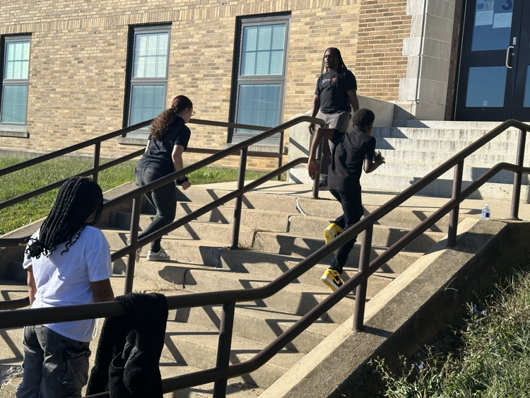 A group of students running up a flight of stairs outside while