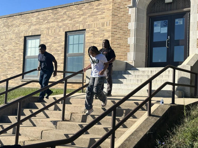 A group of students running down a flight of stairs outside while
