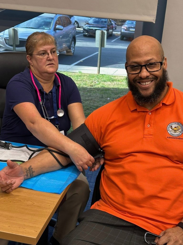 A nurse is measuring a district's staff member's blood pressure in a conference room setting.