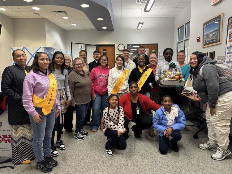 A group of district staff members and students posing together in a lobby area. 